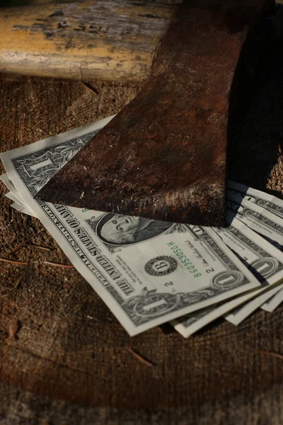 Notas de dólar sob machado velho afiado — Fotografia de Stock