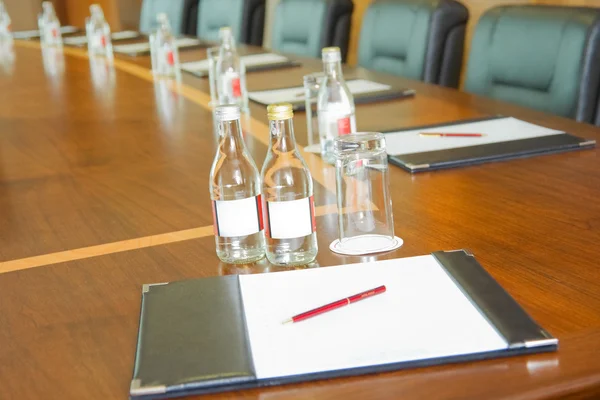 Table with block-notes and bottles of water — Stock Photo, Image