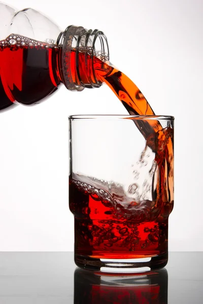 stock image Blackcurrant juice pouring into glass, close up on white background