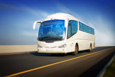 bílý turistický autobus v pohybu na dálnici a rozmazané pozadí