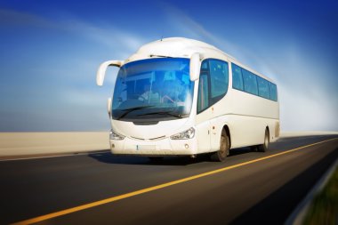 White touristic bus in motion on the highway and blurred background clipart