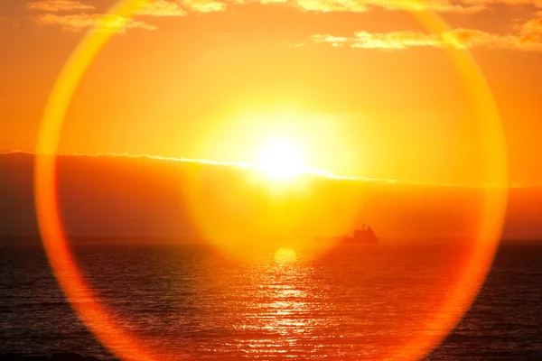 Stock image Beautiful Sunrise over ocean bay and silhouette of ship, lens flare effect