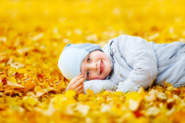 Kisfiú feküdt a sárga levelek — Stock Fotó