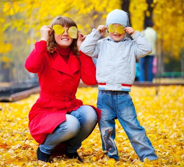 Дитина і мати з осіннім листям — стокове фото