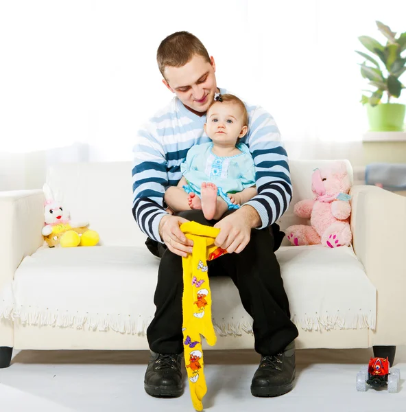 Father Dresses His Baby Daughter Sitting Sofa — Stock Photo, Image