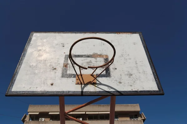 Velho arco de basquete quebrado contra o céu azul — Fotografia de Stock