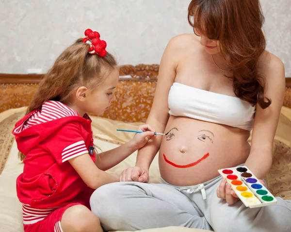 Una figlia sta dipingendo sulla pancia di sua madre — Foto Stock