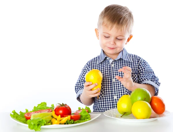 Мальчик и тарелки овощей и фруктов — стоковое фото