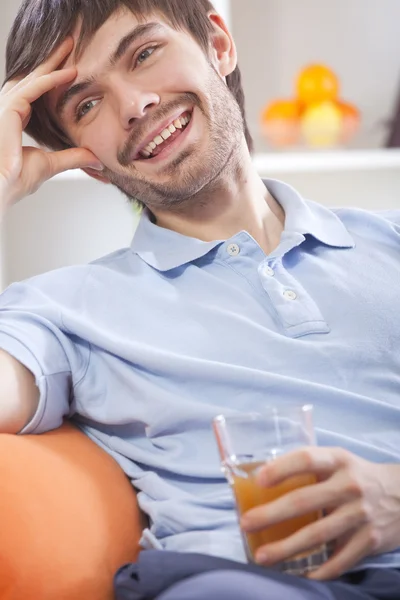 Młody człowiek pijący sok pomarańczowy — Zdjęcie stockowe