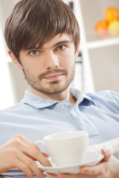 Człowiek z filiżanki herbaty na kanapie — Zdjęcie stockowe