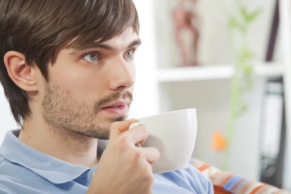 Чоловік п'є чай і дивиться телевізор — стокове фото