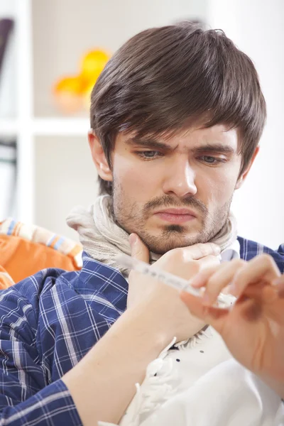 Sick man looking at thermometer — Stock Photo, Image