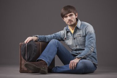 denim giysileri ile eski çanta yere oturan erkek modeli