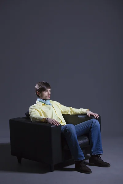 Moda Mężczyzna Żółta Koszulka Siedzi Skórzanym Fotelu — Zdjęcie stockowe