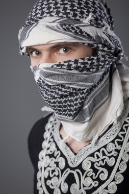 Gri arkaplanda başörtüsü olan Arap bir adamın portresi