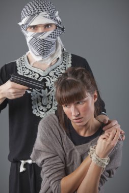Female hostage and hijacker with gun over grey background clipart