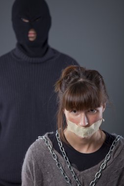 Kidnapped, tied up female hostage and hijacker in balaclava clipart