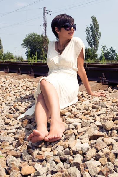 Jovem senhora sentada na estrada de ferro — Fotografia de Stock