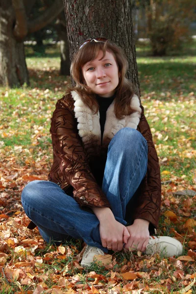 Flickan sitter i höst park — Stockfoto