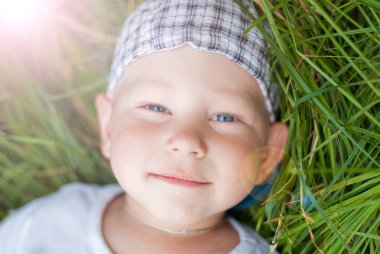 Child lying on the meadow in rays of the sun clipart