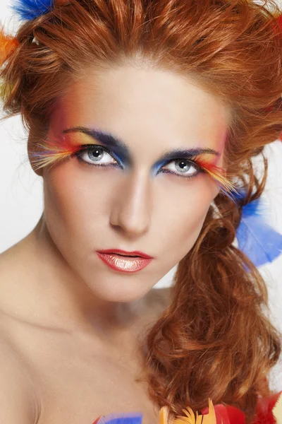 Mujer hermosa con la cara enmarcada en plumas — Foto de Stock