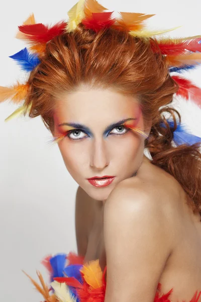 Mujer hermosa con la cara enmarcada en plumas — Foto de Stock