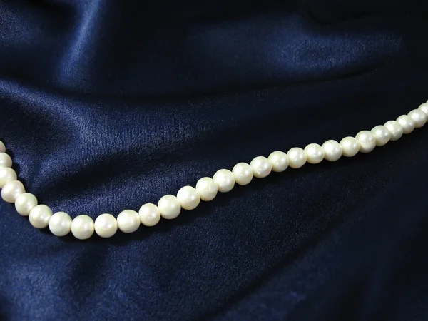 Schöne Weiße Perlen Auf Dem Hintergrund Der Dunkelblauen Seide — Stockfoto