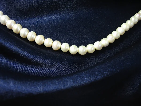Pearls on background the dark blue silk — Stock Photo, Image