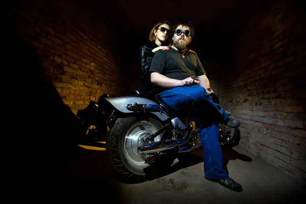 かなりのカップルは バイクに座っています 背景にレンガの壁 — ストック写真