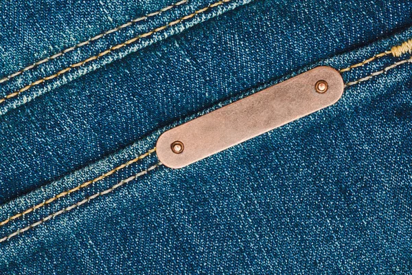 Bronze metal label on jeans — Stock Photo, Image