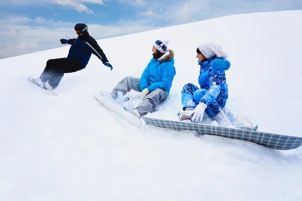 Снег брызгает с доски рядом с двумя девушками — стоковое фото