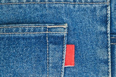 Blue old jeans pocket with empty red label close-up clipart