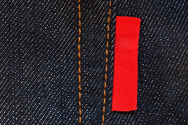 Donkerblauwe jeans achtergrond met lege rood label Stockfoto