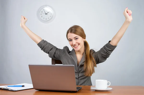 Businesswoman at desk with arms thrown up — Stock Photo, Image