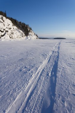 Trace of the snowmobile on the ice clipart