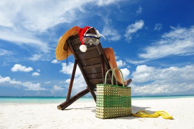 Woman relaxing on the beach in santa's hat clipart