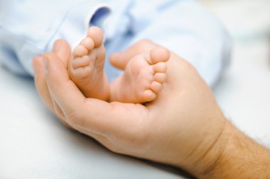 Father holding his newbon baby's feet clipart