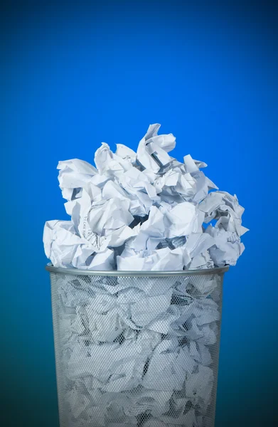 Garbage bin with paper waste against colourful background — Stock Photo, Image
