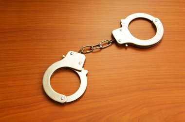 Metal handcuffs on the wooden background clipart