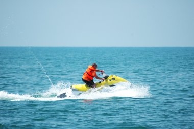 Man driving a motorised scooter at sea clipart