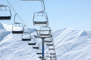 Ski lift chairs on bright winter day clipart
