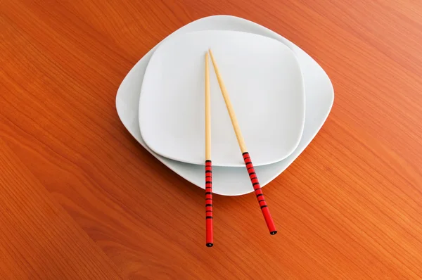 Тарелка с палочками на деревянном столе — стоковое фото