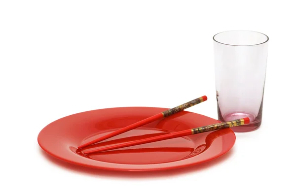 Roter Teller mit Essstäbchen und leerem Glas — Stockfoto