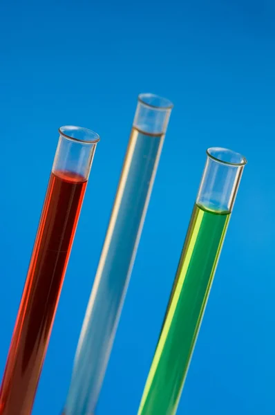Três retortas no laboratório contra fundo azul — Fotografia de Stock