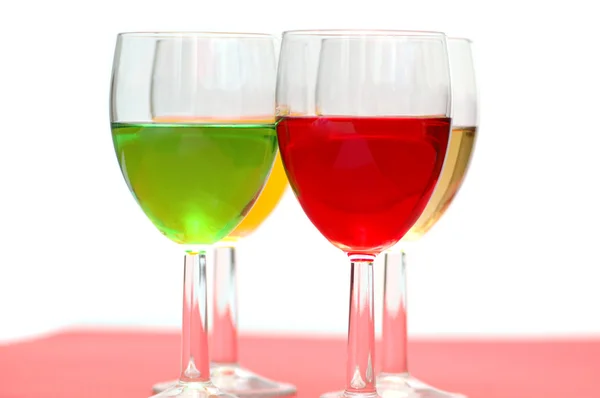Gläser mit Getränken in verschiedenen Farben auf weiß — Stockfoto