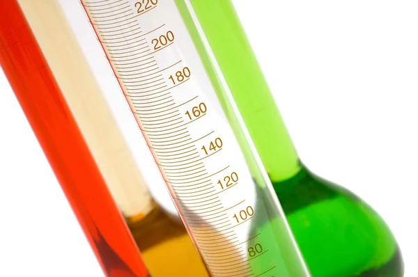 Measuring glass and coloured retorts on white — Stock Photo, Image