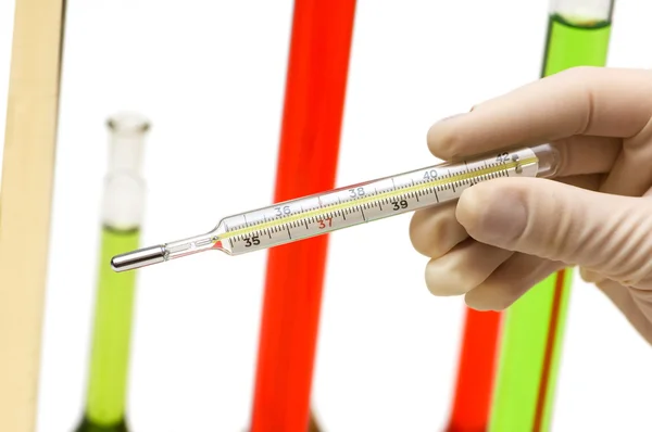 Hand holding thermometer and tubes at the background — Stock Photo, Image