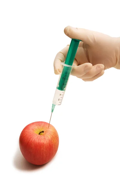 Hand with syringe and red apple on white — Stock Photo, Image