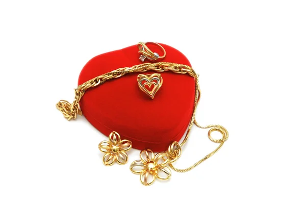 Scatola rossa a forma di cuore e gioielli in oro su bianco — Foto Stock