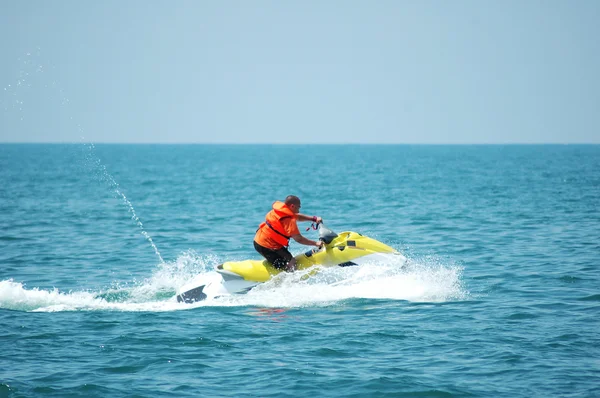 Homem dirigindo uma scooter motorizada no mar — Fotografia de Stock